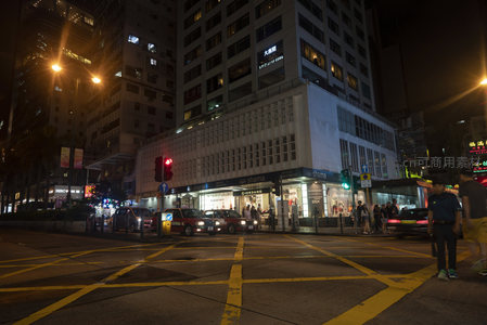尖沙咀路口夜景，黄线斑马线清晰，高楼环抱下的街角商铺灯火通明