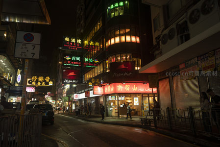 垂直视角下的霓虹峡谷，高楼夹缝中流淌着都市夜韵