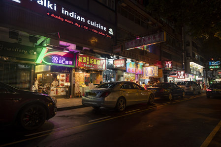繁华夜市街边停靠豪车，印度餐厅与茶餐厅霓虹争艳