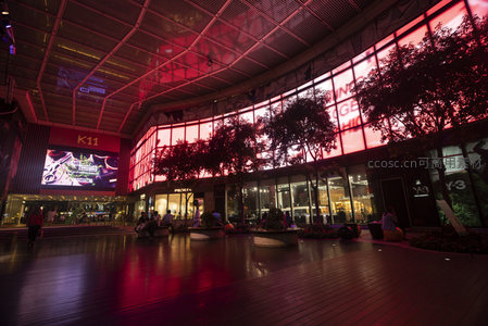 K11室内中庭航拍视角，红光映照下的开放式商业街区与休闲人群