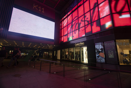 K11入口处动态屏幕与品牌店联动夜景，人流穿梭于光影交错的商业走廊