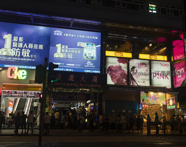 香港重庆大厦夜景霓虹灯闪烁，人群穿梭于繁华商业街