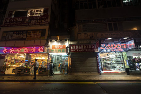 油麻地夜市小巷实景，药房、钱币兑换与成人用品店林立