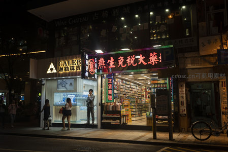 尖沙咀珠宝店与药房夜景，行人驻足橱窗前，自行车停靠路边