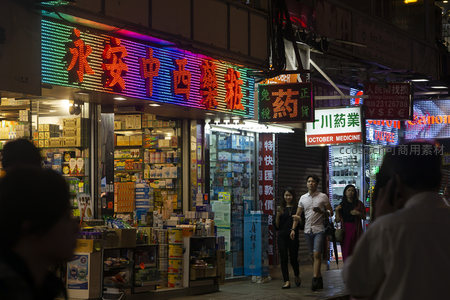 永安中西药庄霓虹招牌下，情侣漫步于香港夜间街市