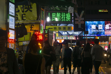 人民币兑换电子屏闪烁，游客穿梭于旺角霓虹广告丛林