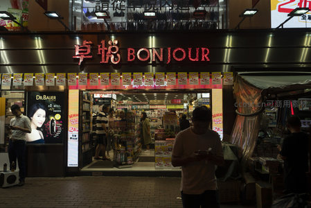 卓悦Bonjour店铺夜景，霓虹灯牌与促销横幅交织的零售街角