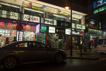 高尔夫用品店林立的夜街，轿车停靠霓虹招牌下光影交错