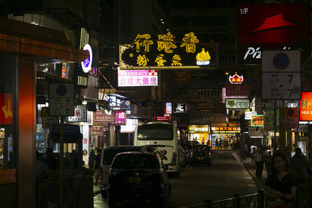 深夜砵甸乍街车流人流交织，披萨店红帽标志与药房招牌共存