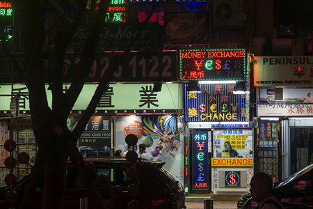 香港货币兑换店霓虹闪烁，树影掩映繁忙街角夜景