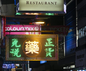霓虹灯下的香港街头夜景，免税药房与餐厅招牌交相辉映
