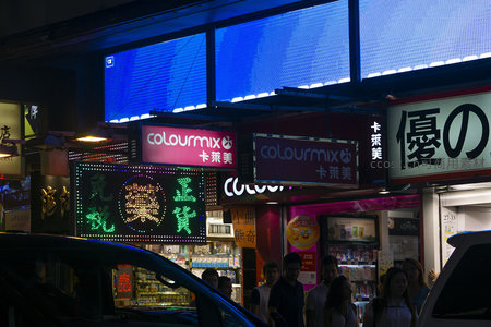 车流穿行于霓虹商圈，Colourmix与优之良品招牌映照行人剪影