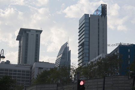 多栋现代办公楼群剪影，蓝天白云下构成都市天际线