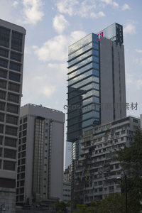 高耸玻璃幕墙大厦与老旧住宅楼并置，新旧城市肌理对比