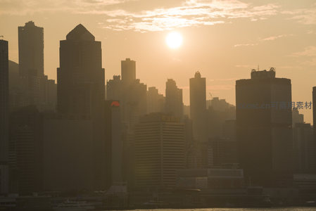 香港维港日落剪影，摩天大楼林立于金色霞光中