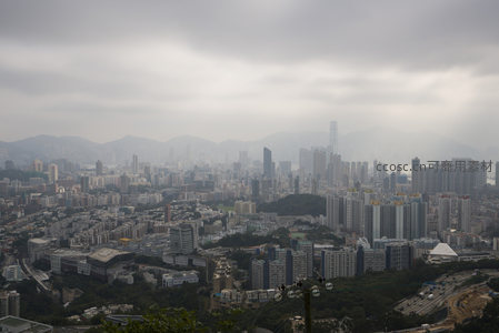 阴云笼罩下的香港城市全景航拍，高楼林立与远山相映成趣