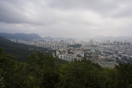 山脊俯瞰港岛密集住宅区，云层低垂下城市与绿意共生共存