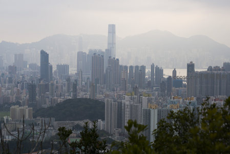 雾霭中的香港城市天际线，高楼林立与远山相映成画