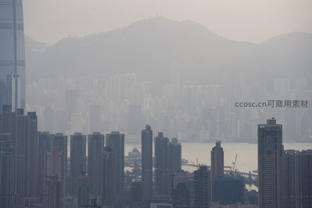高空俯瞰维港两岸，雾中高楼剪影勾勒出香港城市轮廓