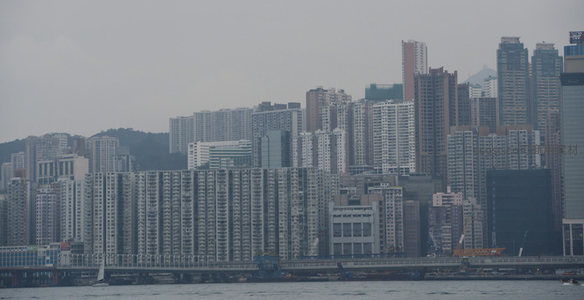 香港密集住宅区临海而建，灰蒙天空下楼群层叠壮观