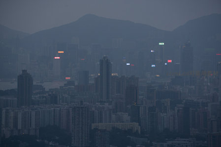 暮色中的香港维港城市天际线，山峦环抱，灯火初上朦胧如画