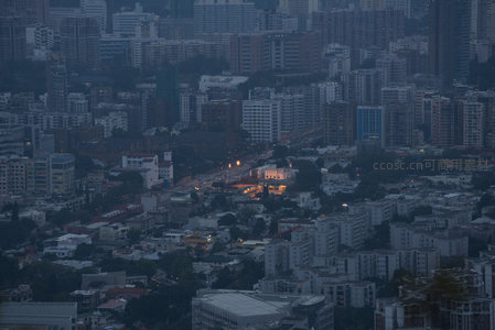 黄昏时分的九龙城区街巷肌理，低矮楼宇与绿坡交织，烟火气悄然升腾