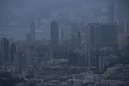 雾霭中的维港两岸，密集楼宇与海面船只构成都市剪影