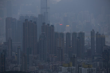 朦胧晨雾里的港岛高层住宅区，灯火零星点缀灰蓝天际