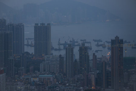 港湾暮色航拍图：货轮停泊、起重机林立，城市剪影笼罩于蓝调薄雾
