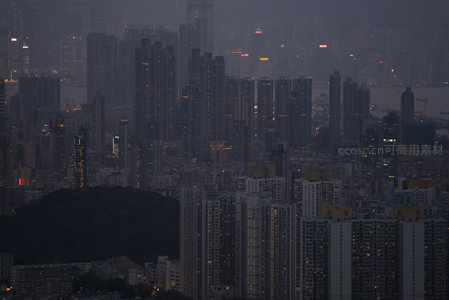 暮色中的香港都市天际线，高楼林立灯火初上，山峦隐现于薄雾之间