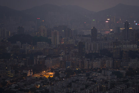 雾霭笼罩的维港畔城市剪影，远山如黛，楼宇灯光星罗棋布