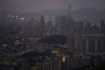 暮色中的香港维港全景，高楼林立灯火初上，远山朦胧如水墨画卷
