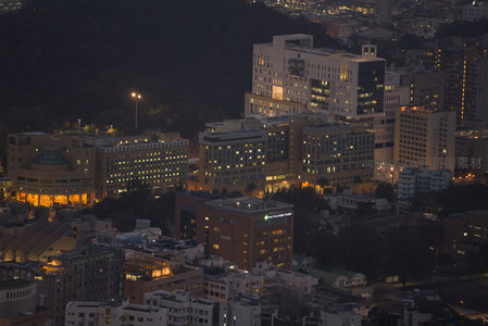山腰俯瞰医院建筑群夜景，暖黄灯光映衬绿植环绕，静谧中透出生机