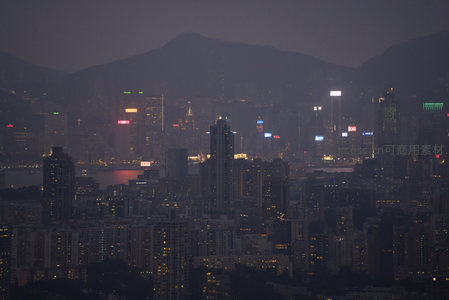 薄雾弥漫的港岛夜景航拍，山影与霓虹交织