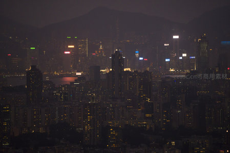 薄雾笼罩下的港岛夜景，万家灯火与远山朦胧交织
