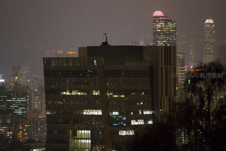 近景现代办公楼夜拍，玻璃幕墙反射点点灯光与远处地标
