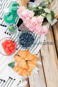 木桌上的粉色玫瑰蓝莓可颂早餐组合