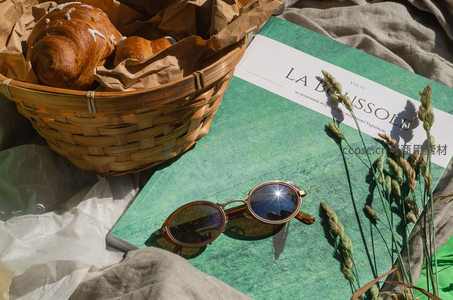 藤编篮中的牛角包与绿色封面杂志静物特写