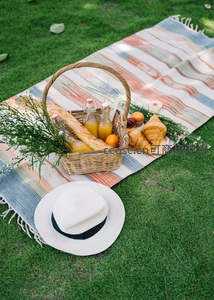 彩色条纹毯上的精致野餐篮，法棍橙汁与羊角面包静物特写