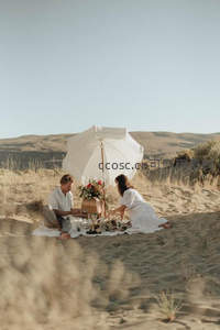 沙丘之上双人野餐场景，白伞轻扬，远山如黛映衬温柔时光