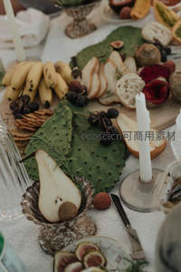 精致野餐台细节特写：仙人掌叶、梨片、无花果与烛光交织的食艺美学