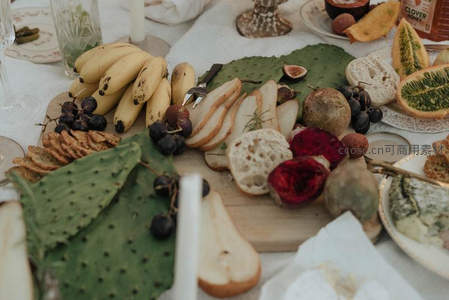 丰盛野餐拼盘俯拍：热带水果、奶酪面包与仙人掌叶的有机组合