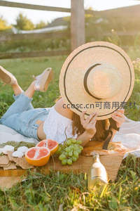 草帽遮面女子躺卧草地野餐场景自然光摄影