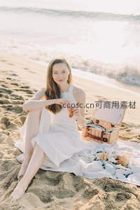 白衣女子海边野餐微笑，篮中美食与海浪相映成趣