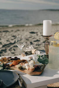 近景海畔餐桌特写：奶酪拼盘、马卡龙、柠檬气泡水与烛光