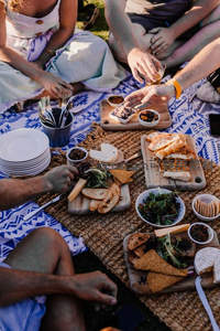 朋友围坐共享野餐时光，手部互动传递食物与欢笑