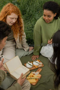 绿野草地上的朋友野餐时光，分享奶酪与书籍的惬意午后