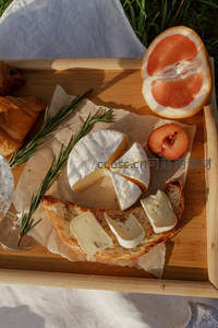 阳光草坪上的法式野餐：布里奶酪、西柚与迷迭香摆盘特写