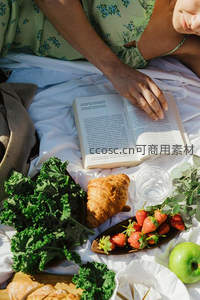 绿裙女子躺卧野餐布上阅读搭配健康蔬果拼盘