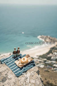 悬崖边俯瞰海岸线的啤酒贝果野餐场景